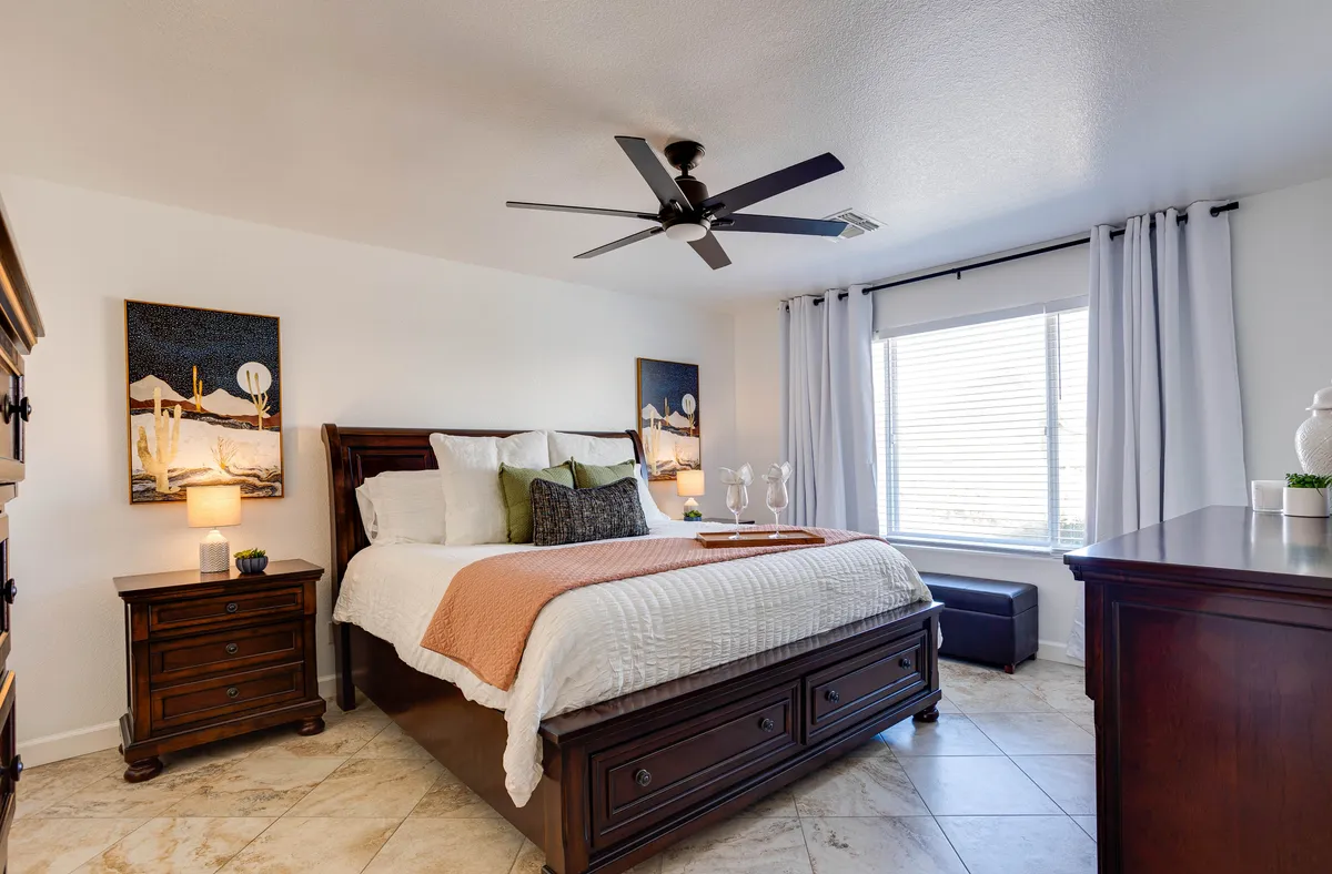 A serene bedroom setting featuring a cozy bed, a window letting in gentle sunlight, a nightstand, and tasteful artwork. The mood is peaceful, ideal for unwinding or waking up refreshed.