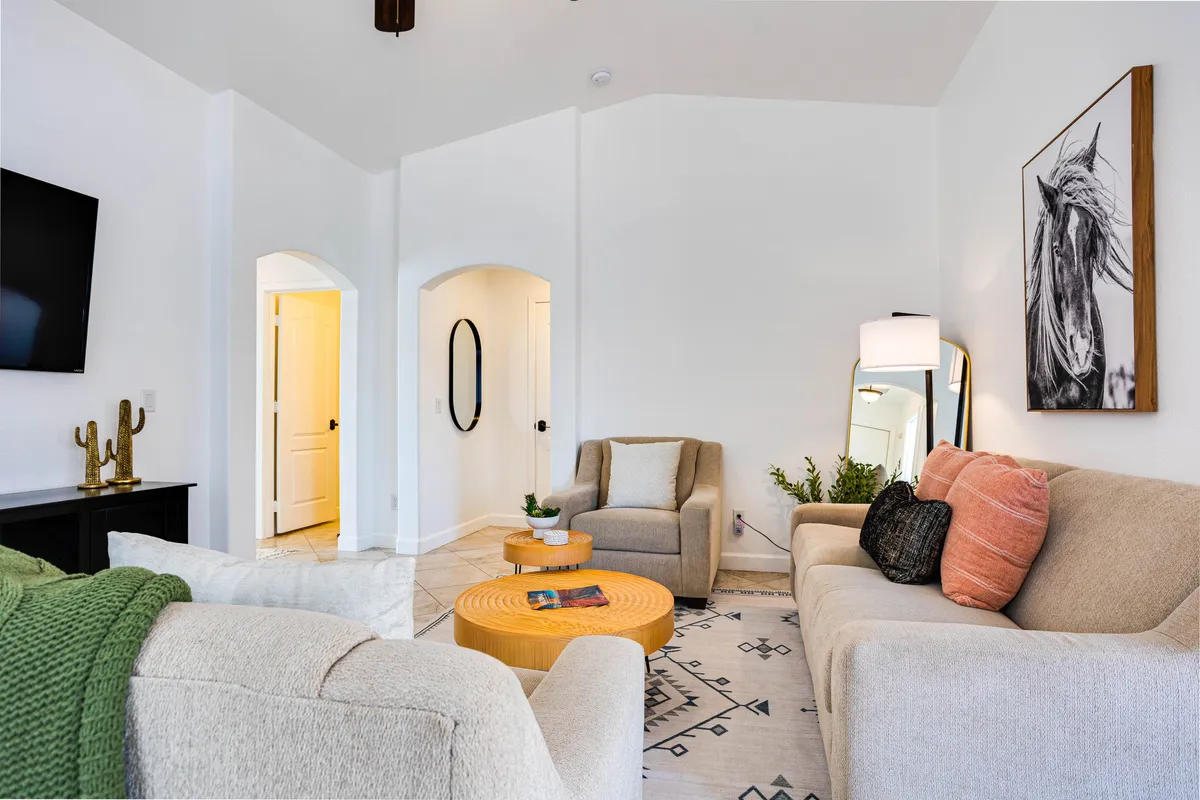 A comfortable living space arranged with a sofa, coffee table, framed artwork, and a warmly lit ambiance. The scene invites socializing, relaxing, and sharing moments with family, all while evoking a welcoming neighborhood feel.