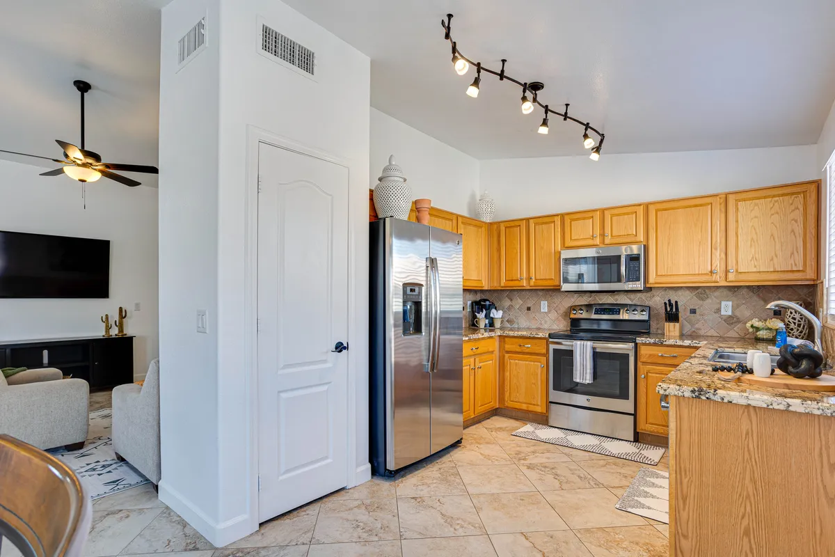 A modern kitchen featuring gleaming granite countertops, stainless steel appliances, wooden cabinetry, and an open layout that connects seamlessly to the living and dining areas. The kitchen is brightly lit and well-equipped for both daily meals and entertaining guests.