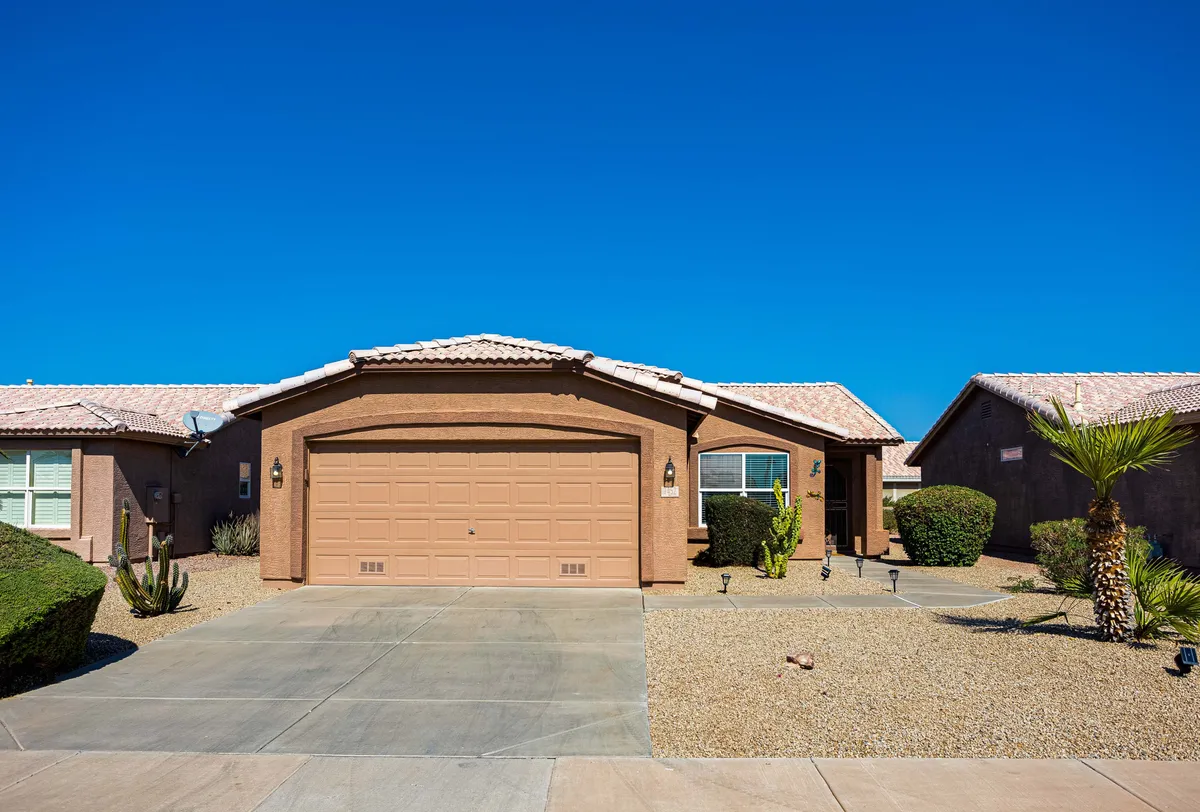A wide exterior view of the residence’s charming front entrance, landscaped yard, and welcoming porch. The scene hints at possibilities for outdoor relaxation, family gatherings, and socializing with neighbors in the Arizona setting.