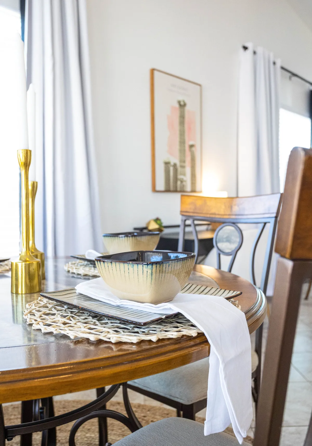 A dining table set for a meal, accented by ceramic bowls, gold candle holder, and colorful artwork on the wall. The table setting is ready for shared meals and lively conversation, reflecting the spirit of entertaining guests and creating memories.