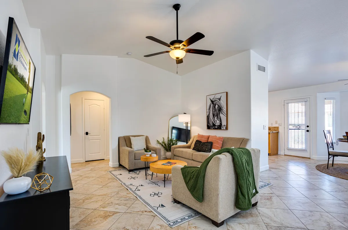A comfortable seating area featuring plush sofas, a wooden coffee table, decorative plant, and vibrant wall art. The space is well-lit and arranged for both conversation and relaxation, with a cozy, welcoming mood.