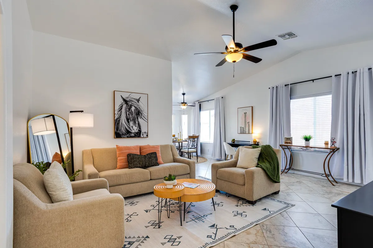 A cozy, inviting community lounge with multiple sofas, a coffee table, artwork on the walls, and softly draped window curtains. The space is designed for group gatherings, recreation, and relaxation, ideal for activities such as social gatherings, game nights, or movie sessions.